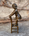 Bronze statues of a little girl in a dress on a stool
