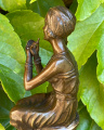 Statue of a woman doing makeup on chair made of bronze